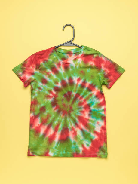 istock T-shirt on a hanger painted in tie dye style on a bright yellow background. 2149761512