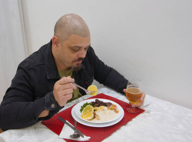A side view of a man eating a typical brazilian dish called feijoada