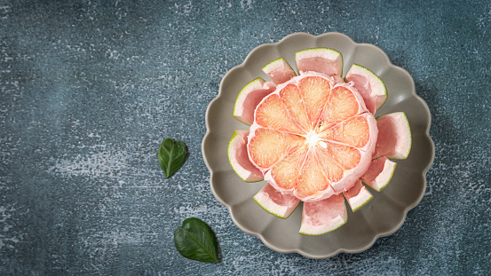 half a grapefruit Juicy fresh meat in a plate on a gray background