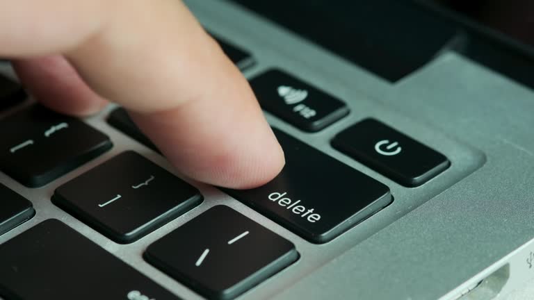 Finger of the computer user, he presses the delete button on the computer keyboard.