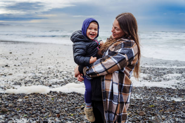 istock Mother holds her toddler son while standing on rocky shoreline 2149767429