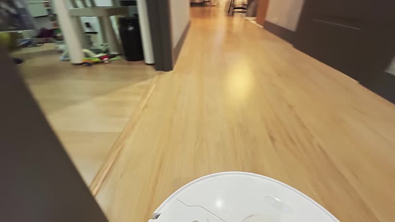 A person is walking on a wooden floor with a white robot in the background
