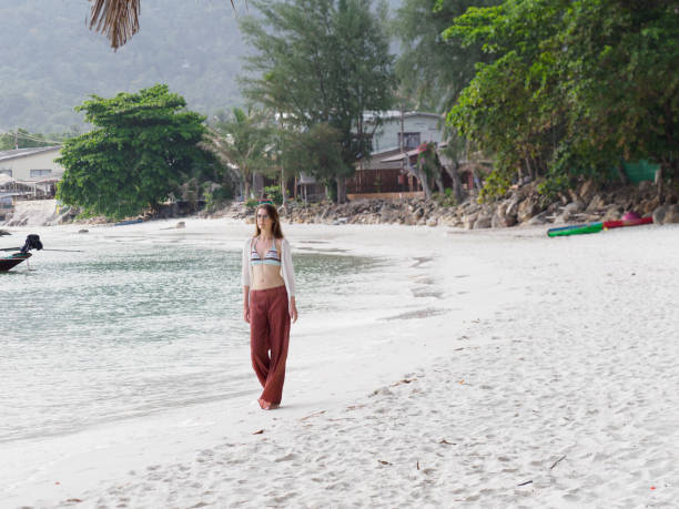 istock Cute woman walking along a stunning white sandy beach 2149767721