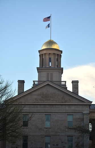 American flag and Iowa state flag flying on the top of the Old Capitol Building at Iowa City, Iowa, Unites States