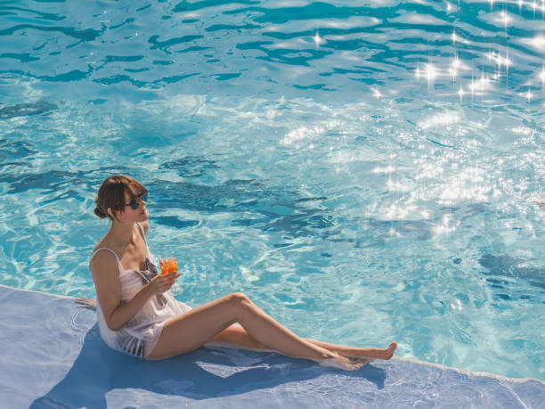 Cute woman with a glass of drink Cute woman with a glass of drink sits near the swimming pool of a cruise ship. Sunny, clear morning. View from above. Closeup, outdoors. Vacation and travel concept arabian sunglasses stock pictures, royalty-free photos & images