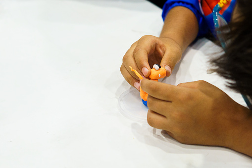 A child is playing with a toy that is orange and blue. The toy is a small figure that is being held in the child's hand. The child is focused on the toy and seems to be enjoying playing with it