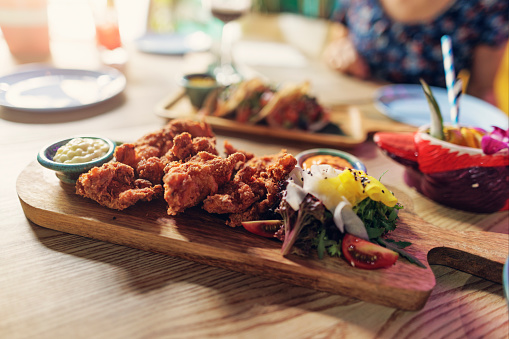 Closeup of deep fried chicken served on a wooden chopping board in a restaurant
Shot with Canon R5