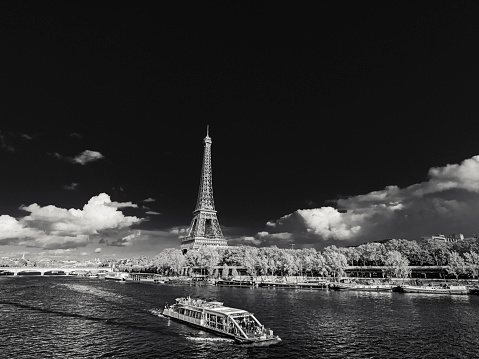 The City of Paris France on October 22, 2023:      Daytime infrared capture of a rive tour as it passes by the Eiffel Tower on the Seine River in Paris France