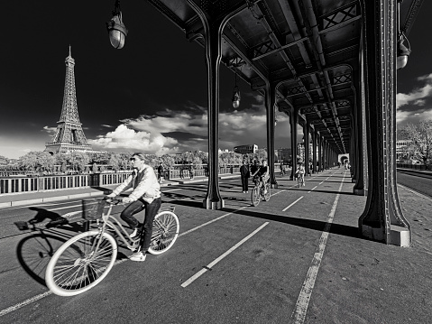 The City of Paris France on October 22, 2023:      Daytime infrared capture of cyclists on the Pont de Bir Hakeim bridge with a view of the  Eiffel Tower in the distant background, in Paris France