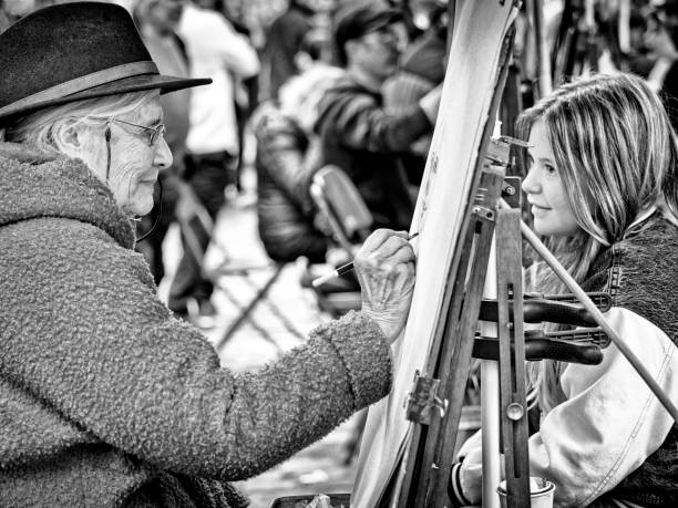 The City of Paris France on October 24, 2023:  Patrons sit for a classic portrait sketch by artists located in a public park in the Montmartre district of Paris France