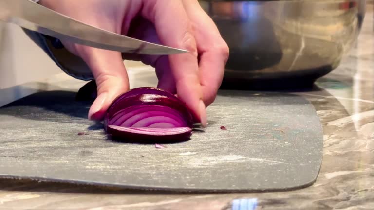 A person is cutting an onion on a cutting board