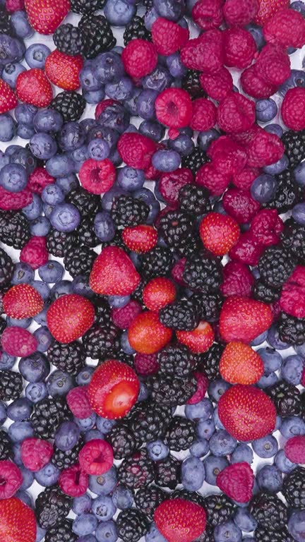 Mix of red blue and black berries dropping in epic slow motion