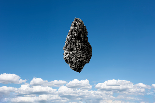 Meteorite floating in mid-air against blue sky.
