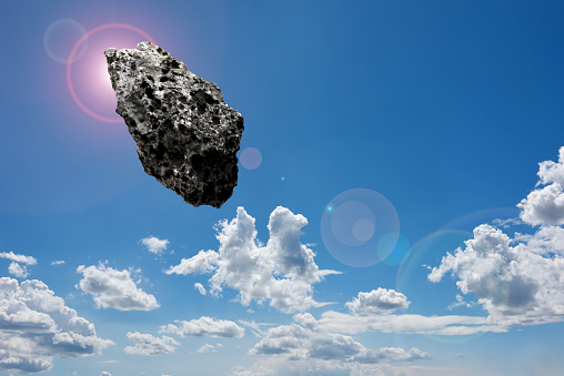 Meteorite floating in mid-air against blue sky.
