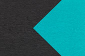 Texture of black paper background, half two colors with turquoise arrow, macro. Craft cerulean cardboard.