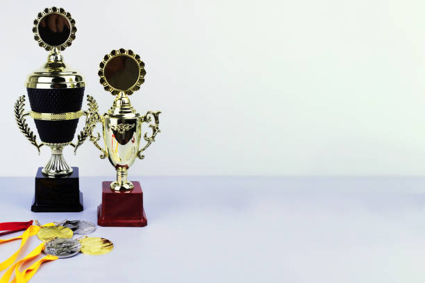 Yellow trophy standing out from teal trophies over teal background. Horizontal composition with copy space. Standing out from the crowd concept.