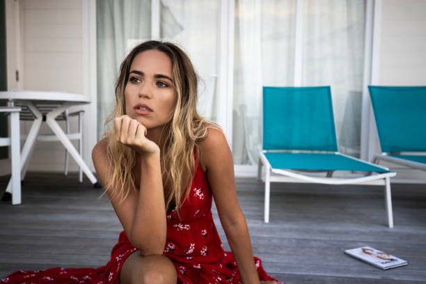 Young woman day dreaming on a patio in front of her house.
