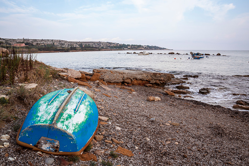 small blue wooden boat abandoned on a beach by the sea