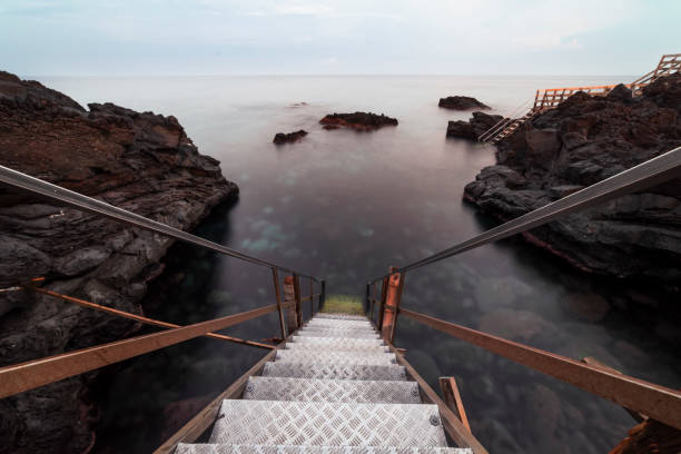 iron staircase leading to the sea, in an inlet between calm sea and lava rock rocks, Ionian Sea