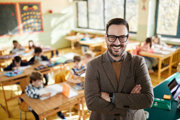 istock Happy elementary teacher with crossed arms in the classroom. 2149773876