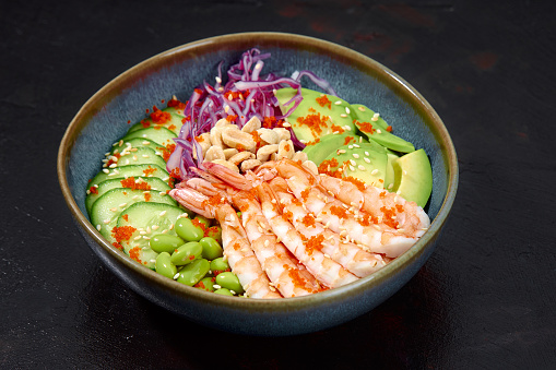 Top view on poke salad with red shrimps and green vegetable in the bowls on gray background. Copy space