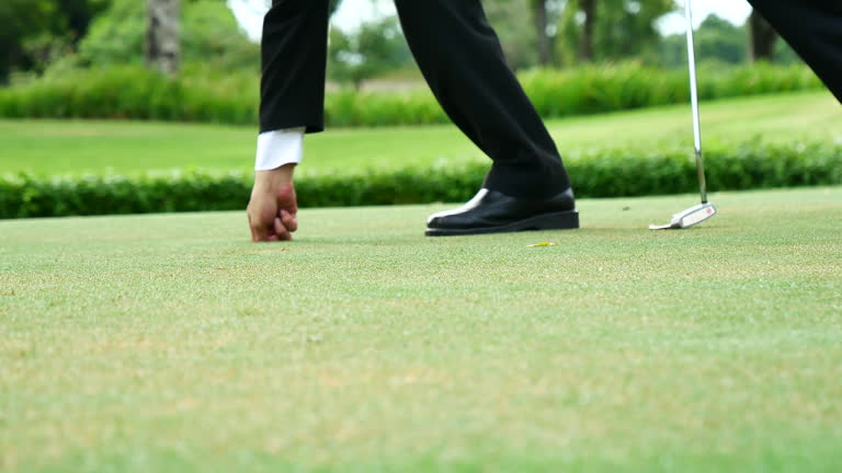 Businessman playing Golf ball practice hit swing on tee in golf club outdoor green field with recreation sport training course. Business men with black Suit driving golf Hobbies