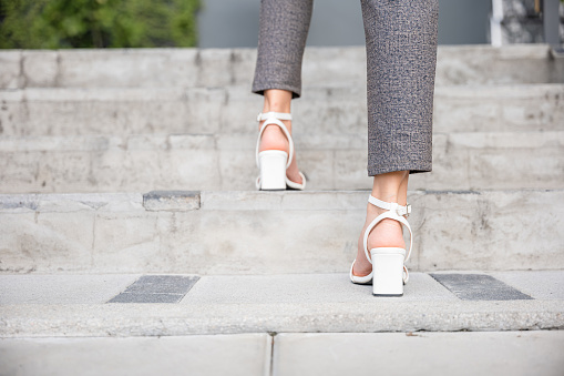 An abstract portrayal of a businesswoman black shoe stepping up city stairs captures the essence of relentless effort, ambition, and progress on the path to success in the modern world.