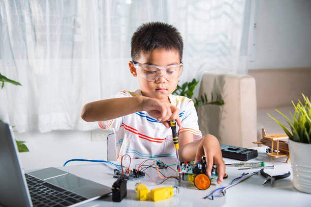 Asian kid boy assembling the A. I. robot car homework project at home