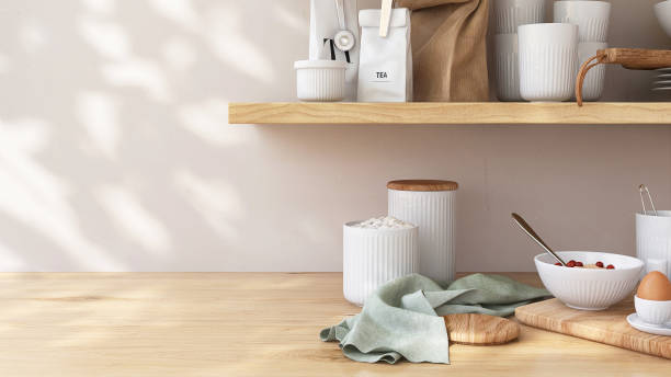 istock Brown wooden countertop table and shelf with cooking kitchenware and ingredient in kitchen in dappled sunlight, leaf shadow on white wall in background 2149775491