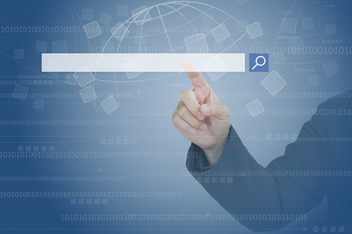 Close-up of a business person's finger touching a futuristic digital search bar on a virtual screen with binary code background.