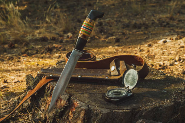 Hunter knife, leather sheath, belt and old army compass in outdoors. Still life with hunting equipment. Close-up