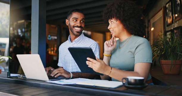 istock Coffee shop, workers and tablet with laptop, remote work and planning strategy for project, online or internet. People, tech and explain for freelance career, copywriters or working on social media and smiling 2149780852