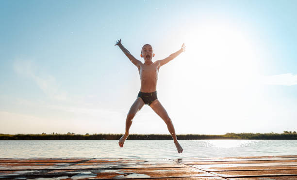 istock Young boy having fun enjoying a summer day jumping at the lake. 2149782601