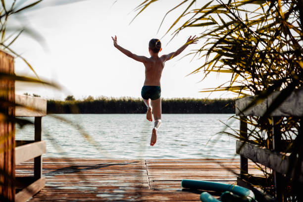 istock Young boy having fun enjoying a summer day jumping at the lake. 2149782622