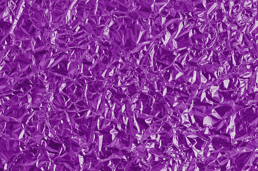 Shiny purple foil texture background, pattern of violet wrapping paper with crumpled and wavy.
