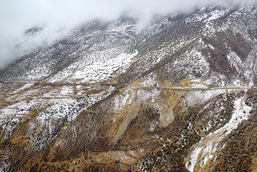 mountain road stretches in the foggy day in Tibetan plateau.