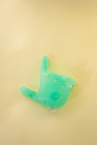 Rubber glove filled with frozen water pointing whit finger against a colored background