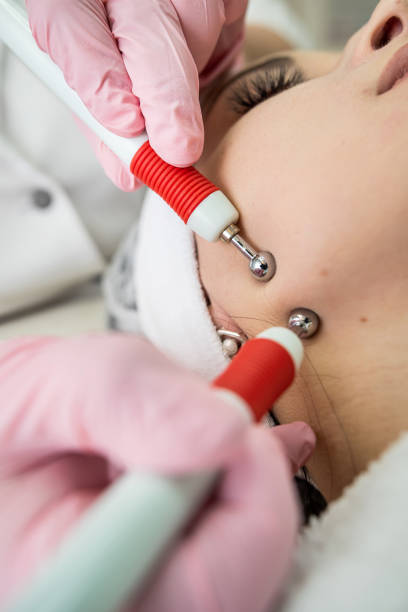 istock beautician performing microcurrent stimulation young woman on face at spa clinic 2149784483