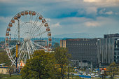 Ferris wheel carousel in a big city in Poland with a view of the urban architecture, dramatic blue sky and mountains in the background
