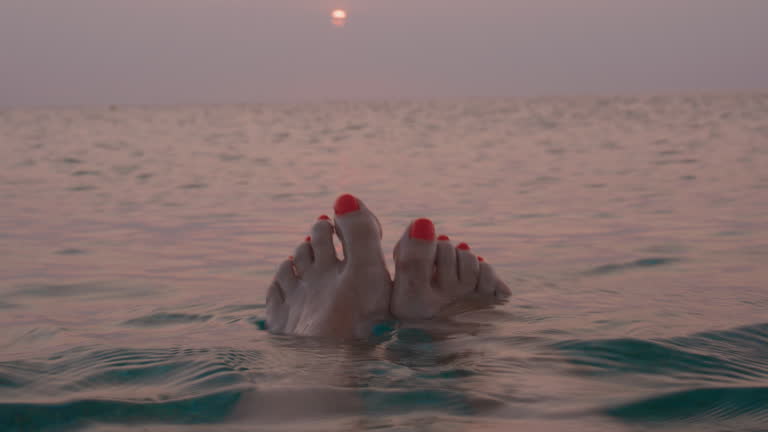 Relaxed feet against sunset sea