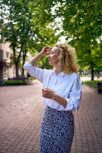 a beautiful middle age woman in 70s, 80s style clothes stretches after work on a sun drenched alley