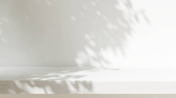 istock Minimal empty white wooden countertop counter in sunlight, leaf foliage shadow on white wall 2149787339