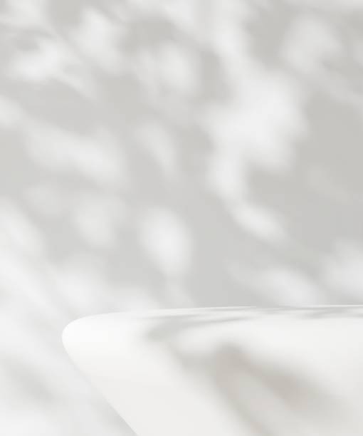 istock White counter table podium in dappled sunlight, leaf foliage shadow on white wall 2149787479