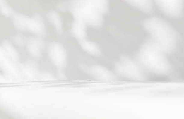 istock White counter table podium in dappled sunlight, leaf foliage shadow on white wall 2149787480