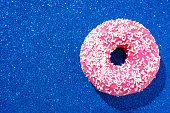 Pink donut with crumbs on a sparkling blue background