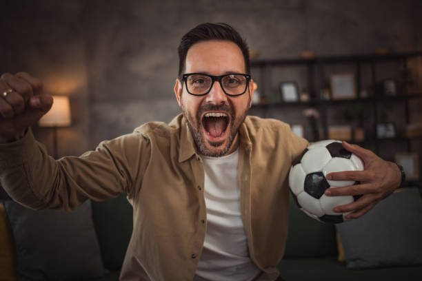 istock A handsome young man is watching a soccer game on TV at home 2149790942