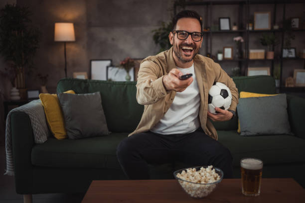 istock A handsome young man is watching a soccer game on TV at home 2149790953