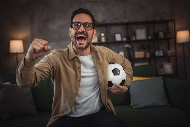 istock A handsome young man is watching a soccer game on TV at home 2149790973