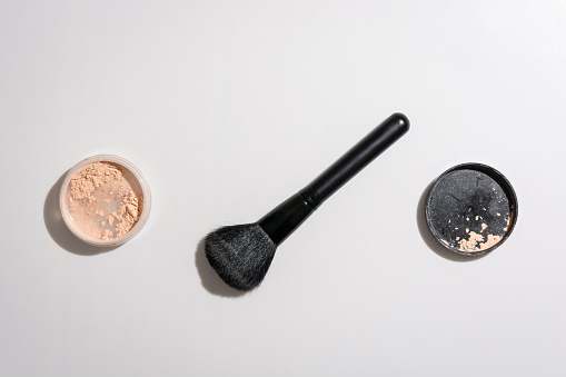 High angle view of a face powder and makeup brush against a white background