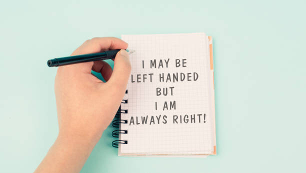 istock I may be left handed but I am right is standing on a notebook, writing with the left hand, pen and table 2149791299